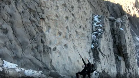 Elio Della Ferrera, Arch. PaleoStelvio Two people look up at the wall of footprints